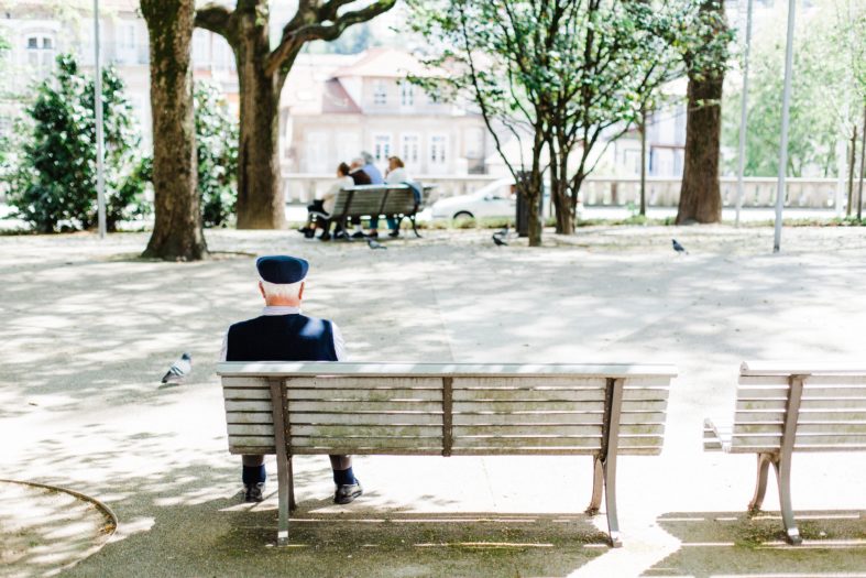 person sitting on beige street bench near trees